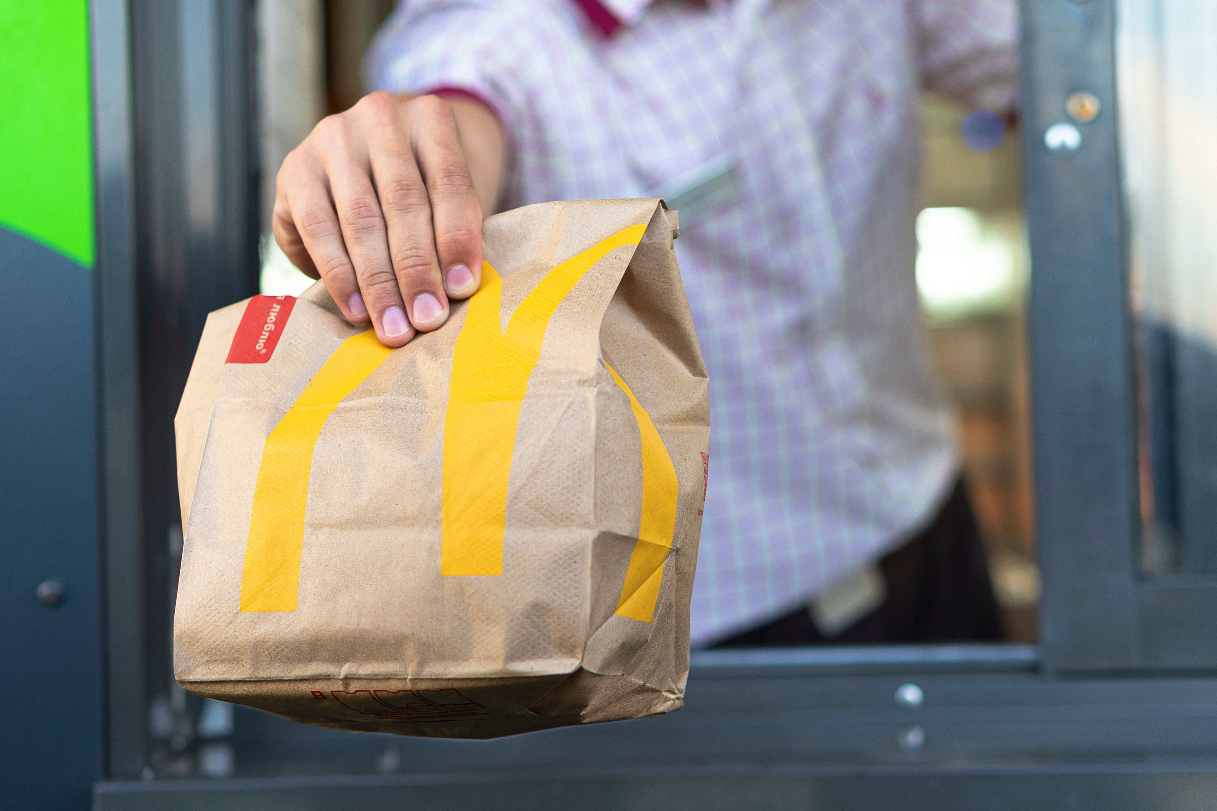 McDonald's employee handing a customer an order from the drive through