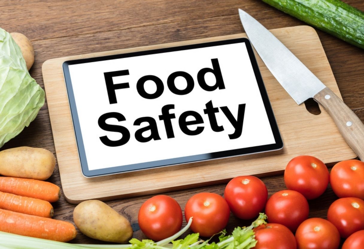 Chopping board surrounded by produce with a sign saying 'Food Safety'